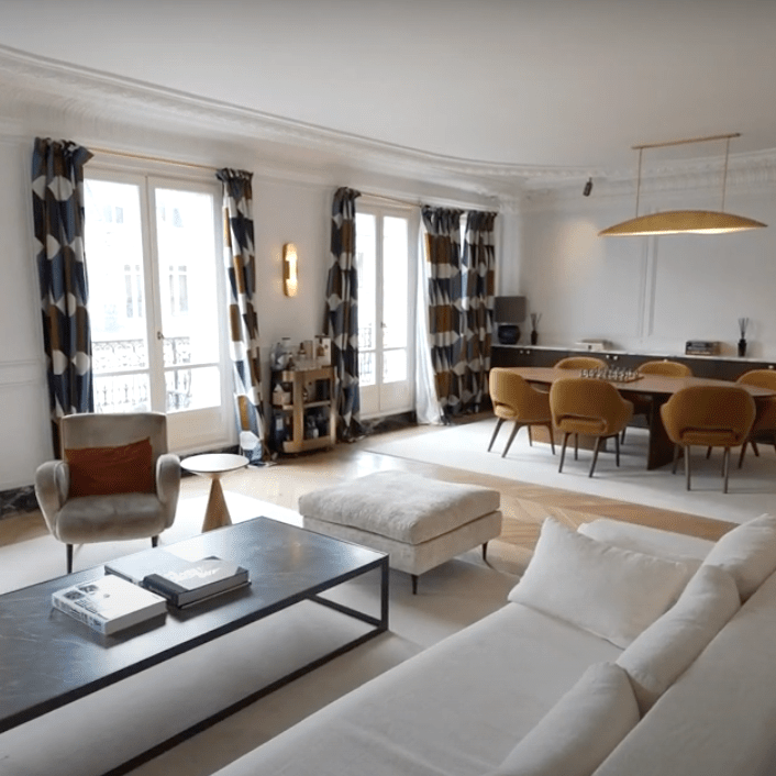 Salon moderne avec un canapé blanc, fauteuils confortables et un meuble de rangement noir.