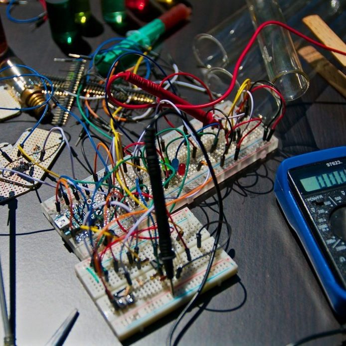 Circuit électronique complexe avec de nombreux fils et un multimètre.