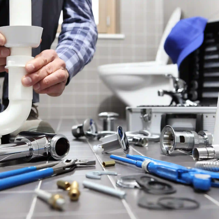 Plombier réparant un siphon avec des outils et des fournitures autour dans une salle de bain dans le 78.