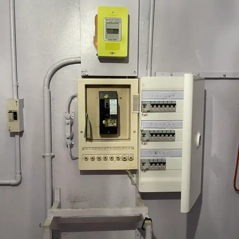 Tableau électrique avec disjoncteurs et compteur, sur un mur gris à Electricien Paris 6