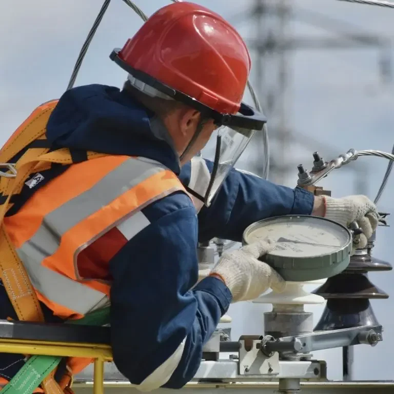 Électricien en tenue de sécurité effectuant des vérifications en hauteur